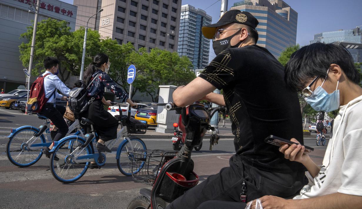 <p>Penumpang yang mengenakan masker menunggu di persimpangan di kawasan pusat bisnis di Beijing, Kamis (5/5/2022). Ibu kota China Beijing pada Kamis (5/5) mulai melonggarkan aturan karantina untuk kedatangan dari luar negeri. (AP Photo/Mark Schiefelbein)</p>