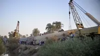 Orang-orang berkumpul di sekitar reruntuhan dua kereta yang bertabrakan di distrik Tahta di provinsi Sohag, sekitar 460 km (285 mil) selatan ibu kota Mesir, Kairo (26/3/2021). Mesir telah dilanda kecelakaan kereta api yang mematikan dalam beberapa tahun terakhir. (AFP)