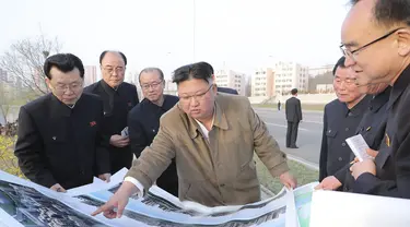 Pemimpin Korea Utara Kim Jong-un memberikan arahan kepada stafnya saat mengunjungi lokasi konstruksi pembangunan gedung apartemen di tepi Sungai Pothong, Korea Utara, Kamis (1//4/2021)..( STR/KCNA VIA KNS/AFP)