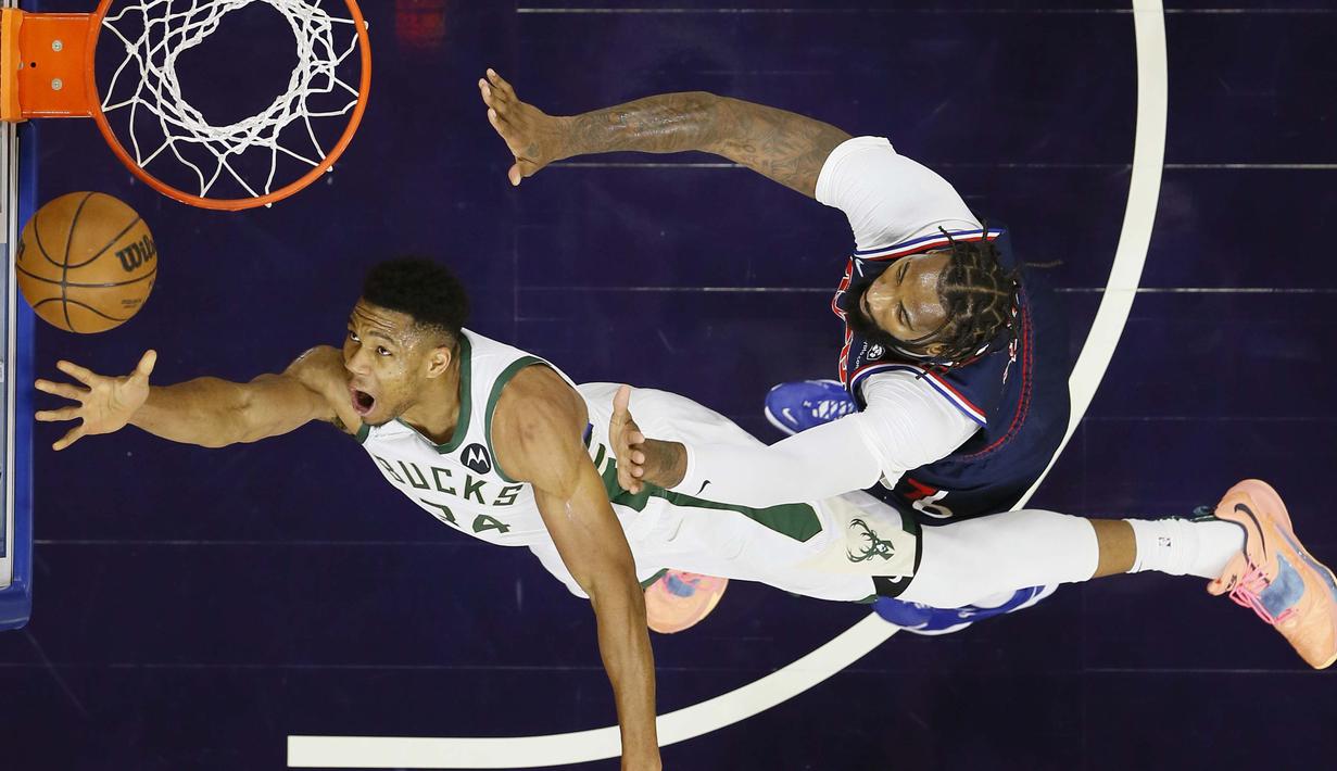 Pebasket Milwaukee Bucks, Giannis Antetokounmpo (kiri) yang dijaga oleh pebasket Philadelphia 76ers, Andre Drummond  berusaha memasukkan bola ke keranjang pada pertandingan bola basket NBA di Philadelphia, Selasa (9/11/2021). (AP Photo/Matt Slocum)