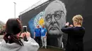 Suporter Leicester City berfoto di depan mural bergambar Claudio Ranieri, (1/5/2016). (Reuters/Eddie Keogh)