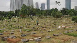 Pekerja membersihkan area makam di TPU Karet Bivak, Jakarta (2/2). Dinas Pertamanan dan Pemakaman telah menerapkan sistem online dalam pelayanan pemakaman di Ibu kota dengan alamat situs pertamananpemakaman.jakarta.go.id. (Liputan6.com/Gempur M Surya)