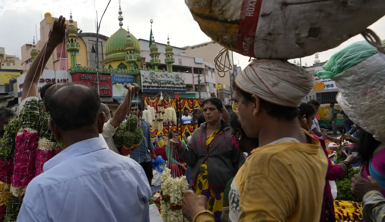Pembeli berjalan melewati pedagang yang menjual bunga di pasar grosir di Bengaluru, India, Rabu (13/4/2022). Orang-orang telah kembali beraktivitas normal setelah pihak berwenang mencabut pembatasan COVID-19 termasuk mengenakan masker wajah di tempat-tempat umum. (AP Photo/Aijaz Rahi)