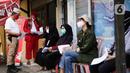 Petugas kepolisian berpakaian pejuang jaman dulu mengecek surat vaksin Covid-19 milik warga di Polsek Pasar Rebo, Jakarta, Selasa (17/8/2021). Para petugas berkostum pejuang jaman dulu memeriahkan HUT ke-76 Republik Indonesia. (Liputan6.com/Angga Yuniar)