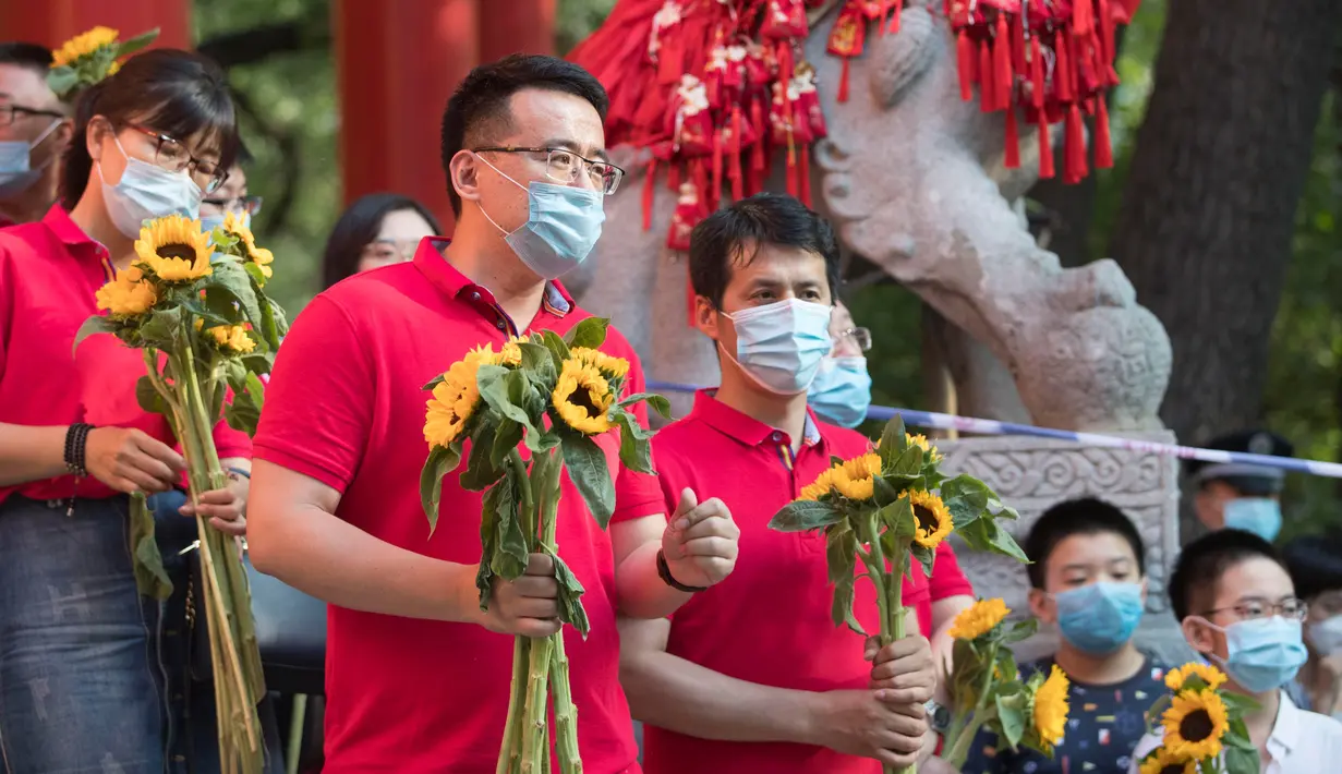 Para guru yang memegang bunga matahari menunggu para peserta di luar lokasi ujian masuk perguruan tinggi di Kota Harbin, Provinsi Heilongjiang, China, pada 8 Juli 2020. Ujian masuk perguruan tinggi nasional telah selesai digelar di beberapa bagian wilayah China pada Rabu (8/7). (Xinhua/Zhang Tao)