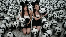 Para model berkostum hitam putih tampak berfoto dengan ribuan panda di Bandara Internasional Hong Kong, Senin (9/6/14). (AFP PHOTO/Philippe Lopez)