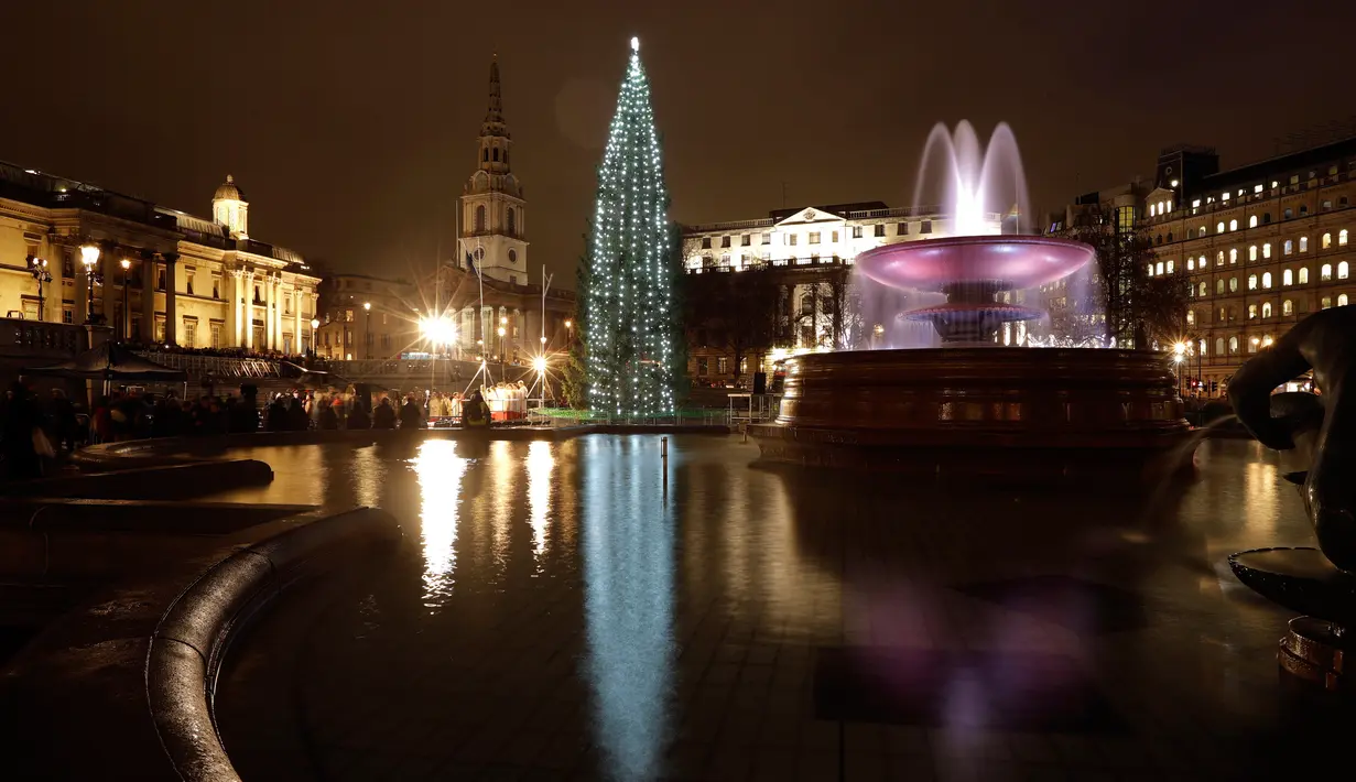 Kolam air mancur memantulkan refleksi pohon natal Norwegia setelah lampunya dinyalakan dalam upacara di Trafalgar Square, London, Kamis (6/12). Pohon cemara itu merupakan pohon natal hadiah tahunan dari kota Oslo kepada rakyat Inggris. (AP/Matt Dunham)