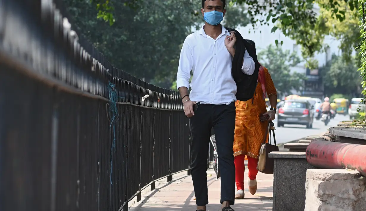 Seorang pria mengenakan masker berjalan di sepanjang jalan di New Delhi (16/9/2020). Total kasus Covid-19 di India melampaui lima juta pada 16 September, data kementerian kesehatan menunjukkan Pandemi meluas cengkeramannya di negara tersebut. (AFP/Sajjad Hussan)
