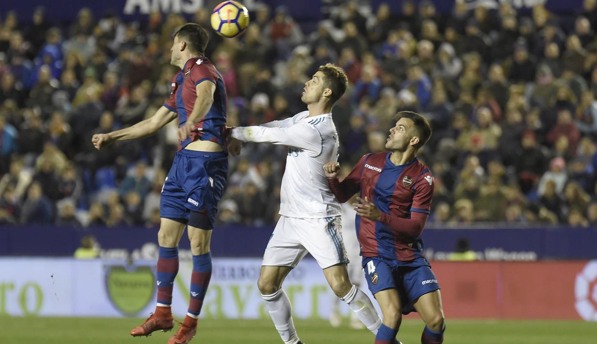 Cristiano Ronaldo (tengah) mencoba menggapai bola saat duel dengan dua pemain Levante  pada laga La Liga Santander di Ciutat de Valencia stadium, Valencia, Spanyol, (3/2/2018). Real Madrid bermain imbang 2-2. (AFP/Jose Jordan)