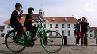 Anak-anak mengenakan masker menggunakan sepeda wisata di kawasan Kota Tua Jakarta, Kamis (29/10/2020). Libur panjang di masa pemberlakuan PSBB transisi Jakarta dimanfaatkan warga untuk mengunjungi lokasi-lokasi wiisata. (Liputan6.com/Helmi Fithriansyah)
