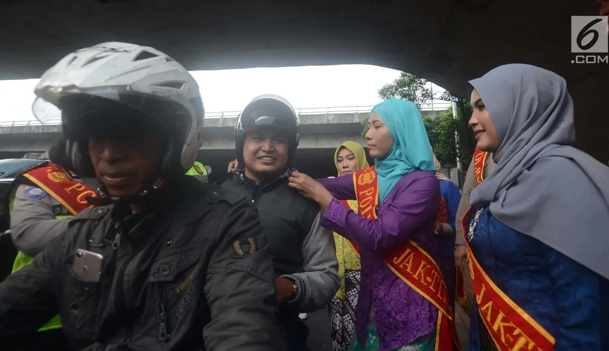 Personel Polisi Wanita (Polwan) Polres Jakarta Timur yang mengenakan busana kebaya, membantu mengenakan helm kepada penggendara motor ketika mengatur arus lalu lintas di Jalan Otista Raya, Jatinegara, Jakarta, Jumat (20/4). (Merdeka.com/Imam Buhori)