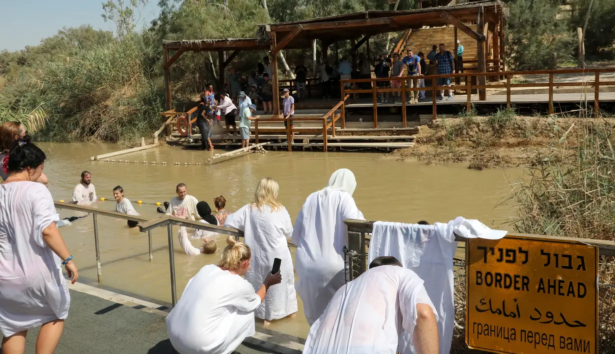 Umat Kristen mengikuti prosesi pembaptisan di Sungai Yordan, Jericho, Palestina, Jumat (13/9/2019). Kegiatan ini untuk mengenang prosesi pembaptisan Yesus Kristus oleh Yohanes Pembaptis. (HAZEM BADER/AFP)