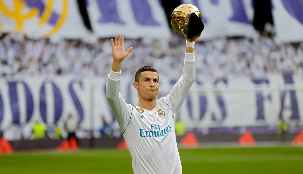 Pemain Real Madrid, Cristiano Ronaldo memamerkan salah satu trofi bola emas Ballon d'Or sebelum laga Real Madrid vs Sevilla di Stadion Santiago Bernabeu, Sabtu (9/12). Ronaldo baru saja meraih trofi kelima penghargaan Ballon d'Or 2017. (AP/Francisco Seco)