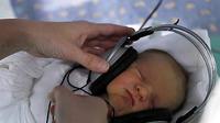Seorang perawat memasang earphones yang memainkan musik santai bagi bayi baru lahir di RS Saca di Kosice, Slowakia timur, Rabu (25/5). (Antara).