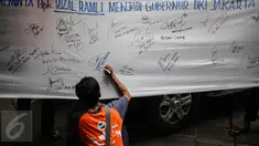 Seorang warga turut memberikan dukungan kepada Rizal Ramli sebagai bakal calon gubernur DKI 2017 dengan menandatangani spanduk, Jakarta, Senin (8/8). Aksi tersebut dilakukan oleh Konferederasi Serikat Pekerja Indonesia (KSPI). (Liputan6.com/Faizal Fanani)