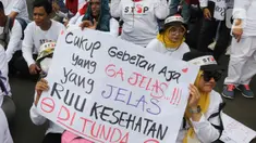 Peserta aksi mengangkat poster berisi pesan penolakan Rancangan Undang-Undang (RUU) Omnibus Law Kesehatan saat aksi di kawasan Patung Kuda Arjuna Wiwaha, Jakarta, Senin (8/5/2023). (Liputan6.com/Herman Zakharia)