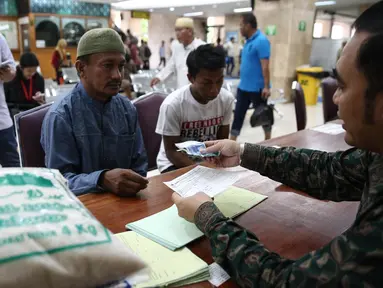 Seorang pria saat membayarkan zakat fitrah pada panitia amil zakat di Masjid Istiqlal, Jakarta, Jumat (1/7). Waktu pembayaran zakat fitrah dibuka hingga malam takbiran. (Liputan6.com/Faizal Fanani) 