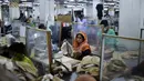 Para buruh bekerja pada stasiun mereka yang dipisahkan oleh sekat sebagai tindakan pencegahan terhadap penularan virus corona COVID-19 di pabrik garmen Civil Engineers Limited, Dhaka, Bangladesh, 17 Agustus 2021. (Munir UZZAMAN/AFP)