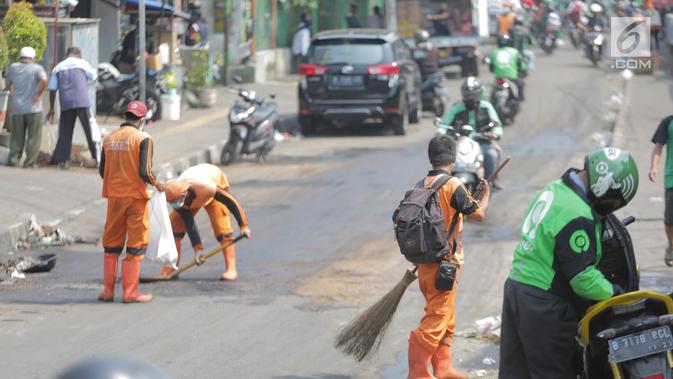 Petugas membersihkan jalan setelah bentrok massa dengan aparat di kawasan Palmerah, Jakarta, Kamis (26/9/2019). Banyak masyarakat yang melintas dan warga sekitar perih pada mata hingga bersin akibat sisa gas air mata. (Liputan6.com/Faizal Fanani)