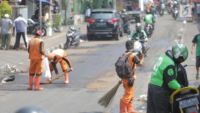 Petugas membersihkan jalan setelah bentrok massa dengan aparat di kawasan Palmerah, Jakarta, Kamis (26/9/2019). Banyak masyarakat yang melintas dan warga sekitar perih pada mata hingga bersin akibat sisa gas air mata. (Liputan6.com/Faizal Fanani)