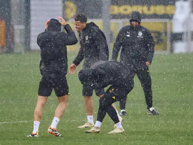 Para pemain Dortmund di sekitar Felix Nmecha (tengah) dikejutkan dengan hujan deras saat sesi latihan di Dortmund, Jerman, Senin (15/4/2024). (Bernd Thissen/dpa via AP)