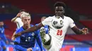 Pemain Inggris, Bukayo Saka, berebut bola dengan pemain Islandia, Albert Gudmundsson, pada laga UEFA Nations League di Stadion Wembley, Kamis (19/11/2020). Inggris menang dengan skor 4-0. (Michael Regan/Pool via AP)