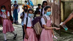 Staf membantu siswa dengan pembersih tangan saat mereka tiba di sebuah sekolah di Allahabad, India, Rabu (1/9/2021). Pemerintah negara bagian melonggarkan lockdown COVID-19 untuk lembaga pendidikan yang memungkinkan siswa menghadiri sekolah tatap muka dengan 50 persen kapasitas. (SANJAY KANOJIA/AFP)