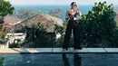Berpose di pinggir kolam renang, Enzy Storia terlihat memesona dan seksi mengenakan bandeau tie crop top berwarna hitam yang dipadu padakankan dengan pallazo kasual warna senada. (Instagram/enzystoria)