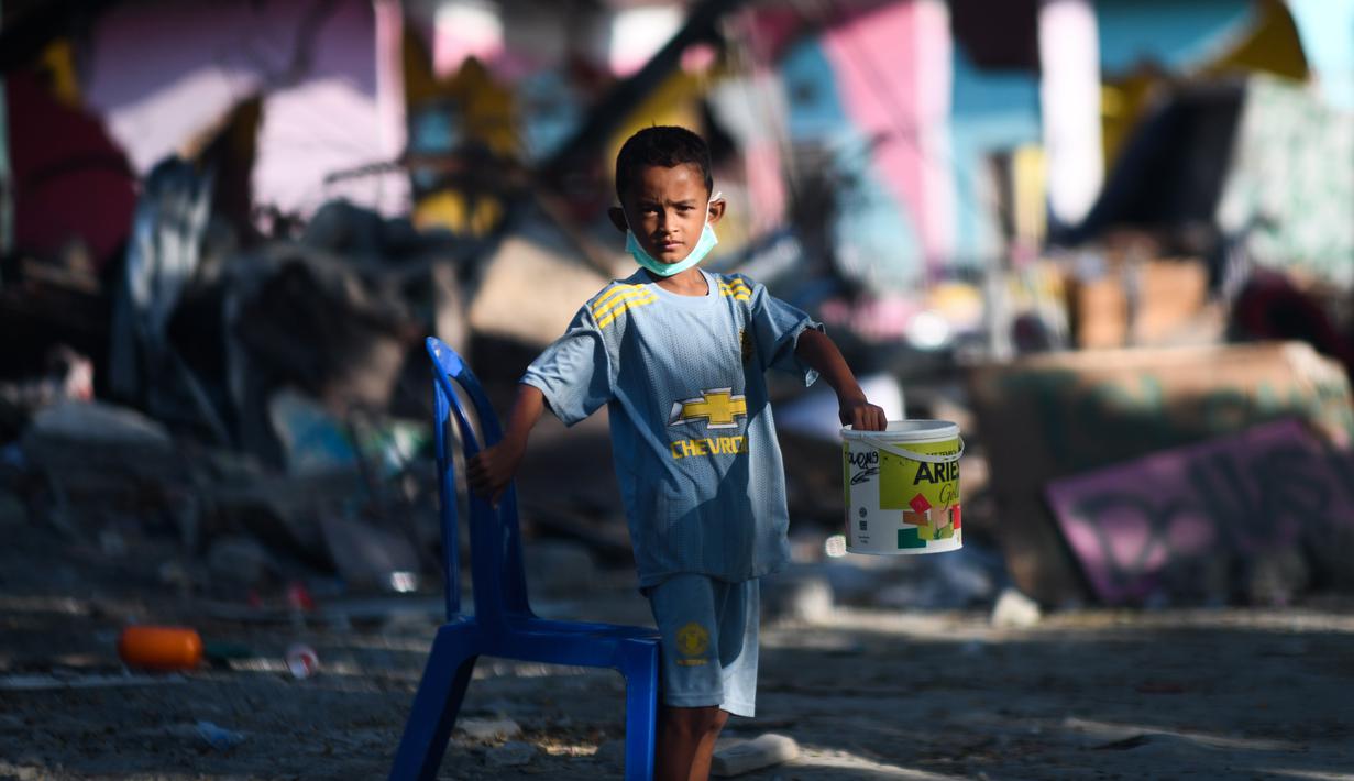Seorang anak yang terkena dampak gempa meminta sumbangan pada pengguna jalan yang melintas di Donggala, Sulawesi Tengah, Jumat (5/10). Akibat terlambatnya pasokan bantuan, mereka terpaksa meminta sumbangan hingga turun ke jalan. (AFP PHOTO / Jewel SAMAD)