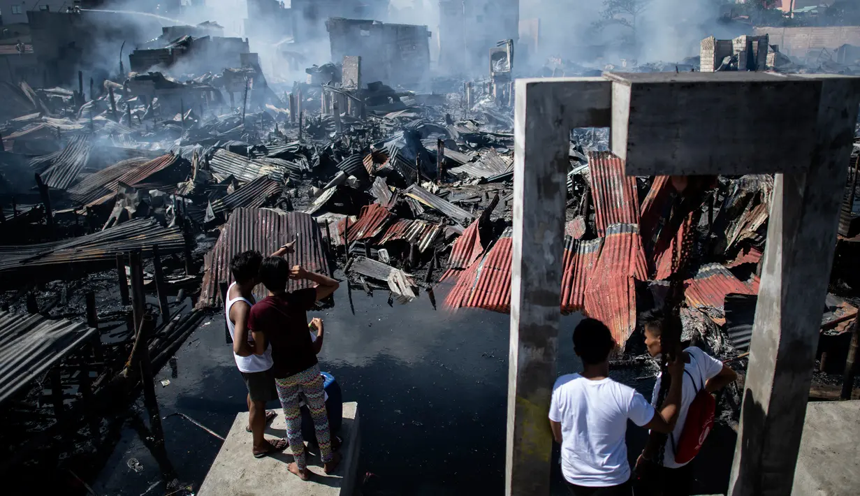 Sejumlah warga melihat rumah-rumah mereka hangus terbakar di sebuah daerah kumuh di Navotas, Manila (8/11). Dilaporkan sekitar 150 keluarga terkena dampak kebakaran tersebut. (AFP Photo/Noel Celis)