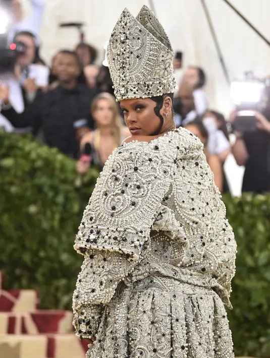 Penyanyi Rihanna berpose untuk fofotgrafer setibanya pada pagelaran Met Gala 2018 di Museum Seni Metropolitan New York, Senin (7/5). Menyempurnakan gayanya, aksesori di kepalanya yang menyerupai mitre atau mitra. (Evan Agostini/Invision/AP)