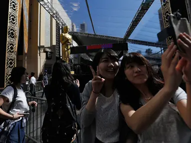 Wisatawan berselfie dengan patung Oscar di luar Teater Dolby selama persiapan jelang 88 Academy Awards di Hollywood, California (24/2). Piala Oscar merupakan penghargaan film Amerika untuk menghargai suatu karya industri film. (REUTERS/Mario Anzuoni)