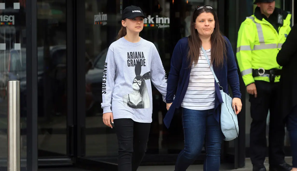 Seorang wanita bernama Amy Trippitt dan putrinya Grace meninggalkan lokasi usai menonton konser Ariana Grande di Manchester, Inggris (23/5). (AP Photo/Danny Lawson)