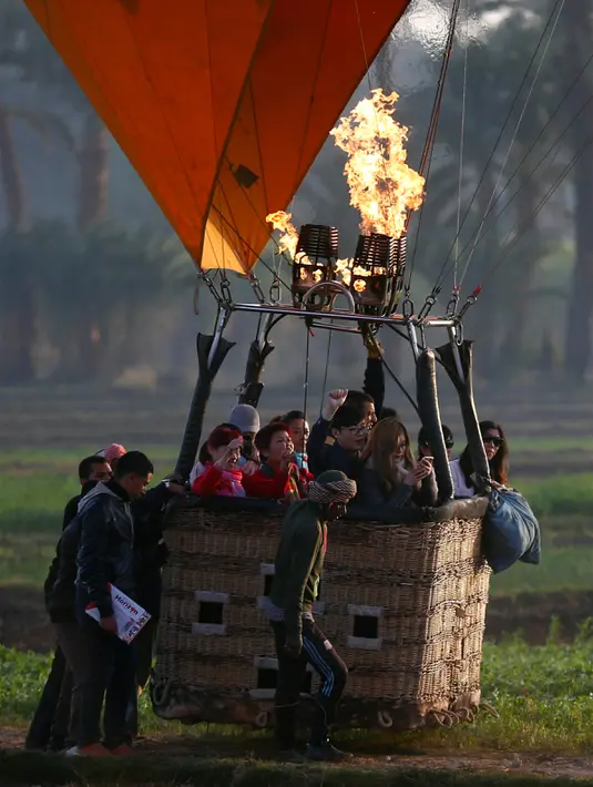 Para kru bekerja membantu para wisatawan saat balon udara panas mendarat di kota Luxor, Kairo, Mesir (13/12). Balon udara panas tersebut juga bagian dari pariwisata kota Luxor. (Reuters/Amr Abdallah Dalsh)