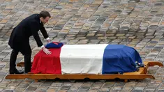 Presiden Prancis Emmanuel Macron meletakkan tangannya di peti jenazah Letnan Kolonel Arnaud Beltrame, setelah secara anumerta memberinya penghargaan perwira tertinggi  dalam upacara nasional di Hotel des Invalides, Paris, Rabu (28/3). (AP/Christophe Ena)