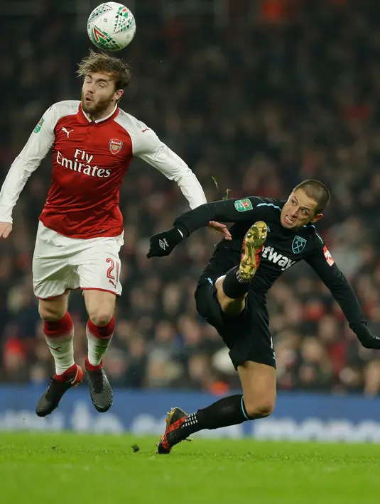 Pemain Arsenal, Calum Chambers menyundul bola ketika bersaing dengan pemain West Ham United Javier Hernandez dalam lanjutan pertandingan Liga Inggris di Stadion Emirates, Minggu (22/4). Arsenal mampu unggul telak dengan skor 4-1. (AP/Alastair Grant)