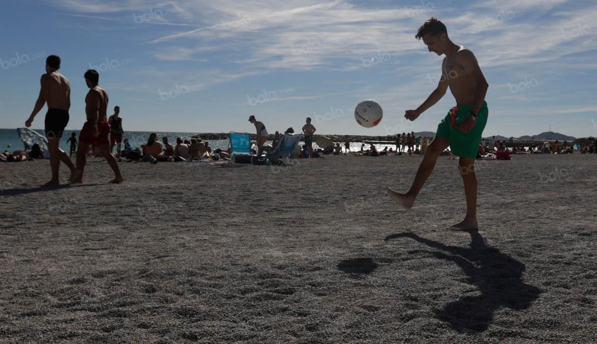 Seorang anak bermain bola di tepi Pantai Prado yang merupakan salah satu garis pantai yang sering dijadikan turis untuk berjemur. (Bola.com/Vitalis Yogi Trisna)