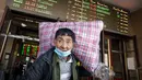 Seorang pelancong yang mengenakan masker untuk melindungi dari penyebaran virus corona membawa kopernya saat dia berjalan keluar dari pintu keluar di Stasiun Kereta Api Beijing di Beijing, Kamis (28/1/2021).  (AP Photo/Mark Schiefelbein)
