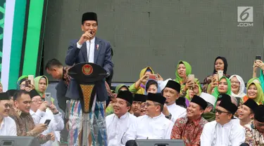 Presiden Joko Widodo atau Jokowi memberi sambutan dalam Harlah ke-73 Muslimat NU di SUGBK, Jakarta, Minggu (27/1). Jokowi datang dengan mengenakan kain sarung, jas, dan kopiah hitam. (Liputan6.com/Johan Tallo)