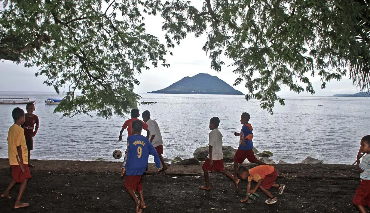 Anak-anak di Alor bermain bola dengan lapangan dipinggir pantai, mereka menikmati waktu pulang sekolah dengan bermain bersama. (Bola.com/Nicklas Hanoatubun)