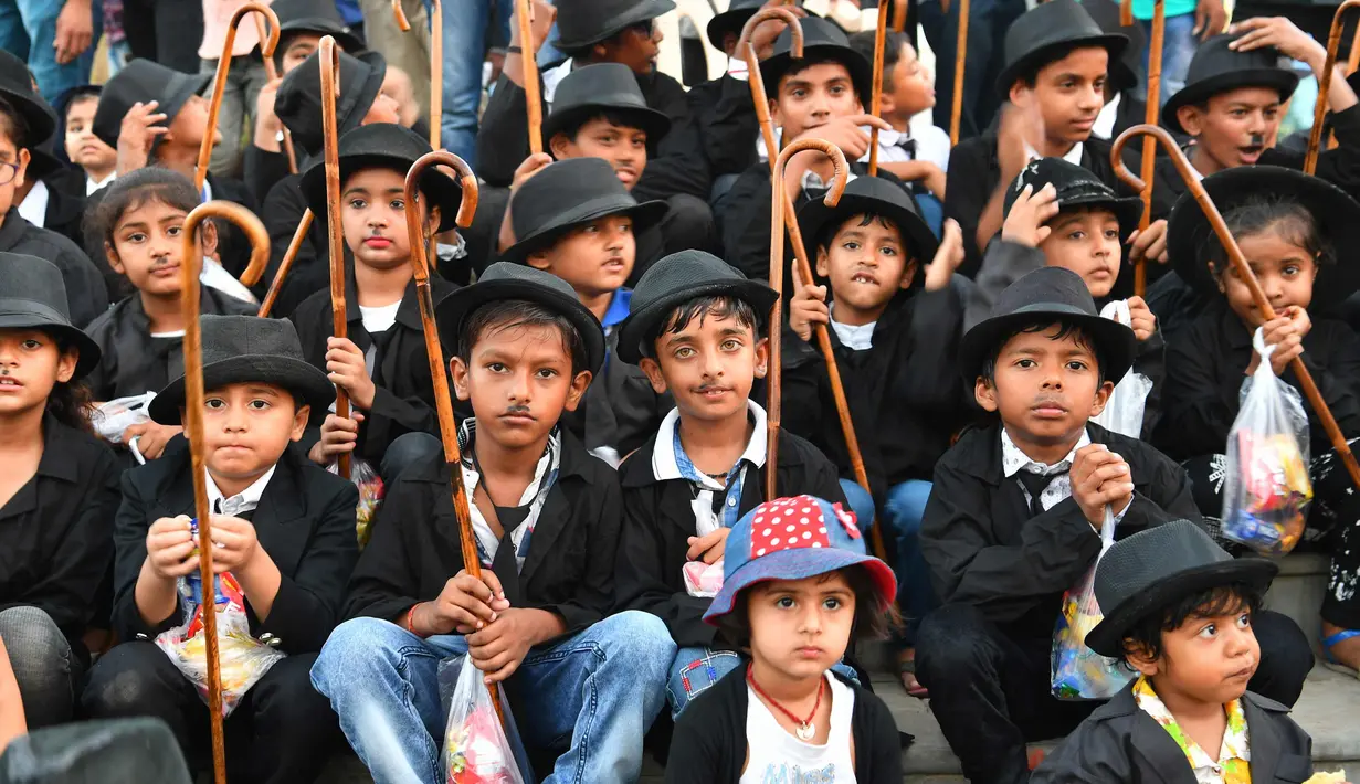 Sejumlah anak berpenampilan seperti Charlie Chaplin berpose memperingati ulang tahun Charlie Chaplin ke-129 di Adipur, sekitar 60 km barat laut Bhuj di negara bagian Gujarat, India barat (16/4). (AFP Photo/Indranil Mukherjee)