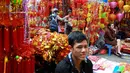 Pemilik toko menunggu pelanggan untuk membeli dekorasi Tahun Baru Imlek atau perayaan Tet di sebuah pasar pusat Kota Tua Hanoi, Senin (28/1). Di Vietnam, tahun baru imlek dikenal dengan nama Tet Nguyen Dan atau disingkat Tet. (Manan VATSYAYANA/AFP)