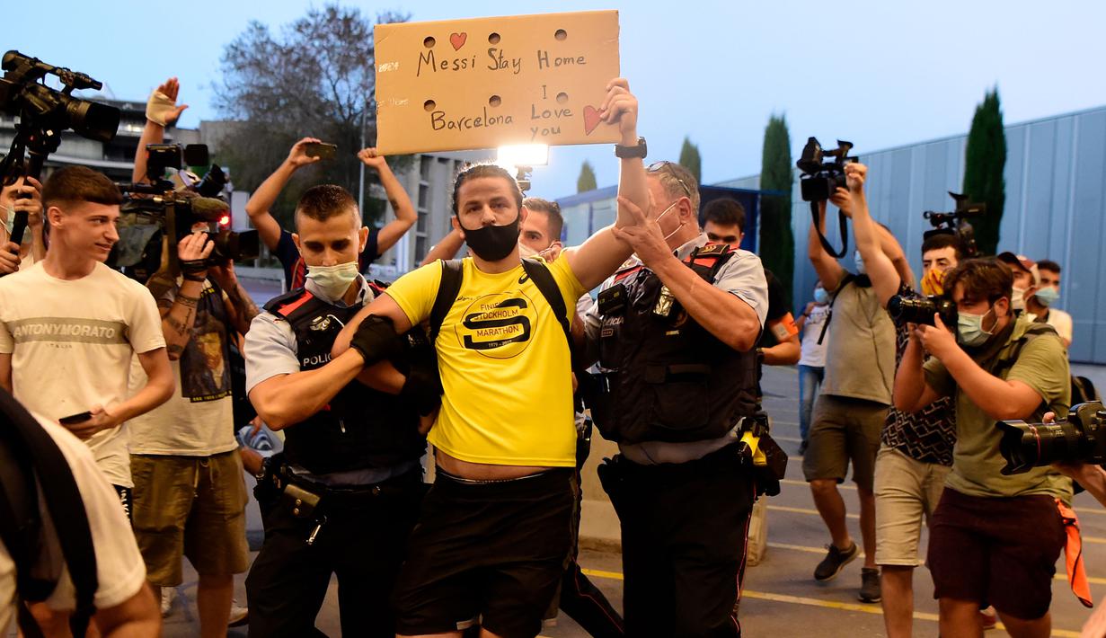 Suporter dikawal keluar oleh petugas keamanan saat protes di kantor Barcelona, Rabu (26/8/2020). Dalam aksi tersebut fans meminta Lionel Messi bertahan dan menuntut Josep Maria Bartomeu mundur dari jabatannya. (AFP/Pau Barrena)