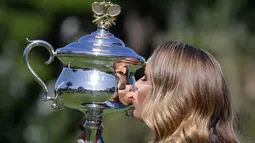 Caroline Wozniacki mencium piala Australia Terbuka 2018 di Royal Botanical Gardens di Melbourne, Australia, (28/1). Petenis Denmark ini berhasil mengalahkan petenis Rumania Simona Halep 7-6, 3-6, 6-4 di babak Final. (AP Photo / Dita Alangkara)