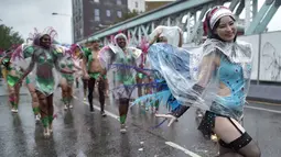 Para penari tampil mengenakan mantel plastik saat beraksi di tengah hujan dalam karnaval Notting Hill, London, Inggris (31/8/2015). Karnaval Notting Hill diadakan untuk merayakan budaya Karibia yang sudah dikenal sejak 1960-an. (AFP PHOTO/LEON Neal)