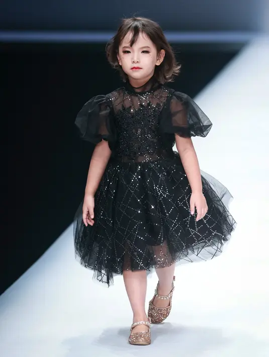 Seorang model anak membawakan koleksi busana dari KUNJIE karya Liu Shuming pada gelaran China Fashion Week di Beijing, China, Selasa (27/10/2020). (STR / AFP)
