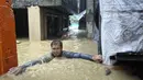 Seorang pria mengatasi banjir setinggi leher di desanya yang disebabkan oleh Topan Doksuri di kota Laoag, provinsi Ilocos Norte, Filipina utara, Rabu, 26 Juli 2023. (AP Photo/Bernie Sipin Dela Cruz)