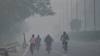 Pesepeda melintas di sepanjang jalan di tengah kondisi kabut asap yang menyelimuti New Delhi, India, Minggu (7/11/2021). Ibu kota New Delhi diselimuti udara beracun pada Sabtu kemarin karena tingkat polusi yang sangat tinggi pasca-perayaan festival besar agama Hindu. (Money SHARMA/AFP)