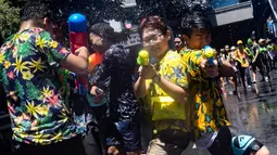 Orang-orang bersuka cita saling menyemprotkan air selama Festival Songkran di Silom Road, Bangkok, Jumat (13/4). Songkran dikenal dengan nama festival air karena warga Thailand percaya air akan menghapus nasib buruk. (LILLIAN SUWANRUMPHA/AFP)