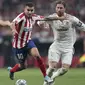 Penyerang Atletico Madrid, Angel Correa (tengah) menggiring bola dari kejaran bek Real Madrid, Sergio Ramos (kanan) selama pertandingan lanjutan La Liga di stadion Wanda Metropolitano, Spanyol (28/9/2019). Madrid dan Atletico bermain imbang 0-0. (AP Photo/Bernat Armangue)